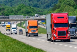 Several trucks on highway with traffic