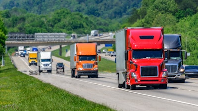 Several trucks on highway with traffic