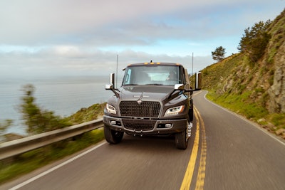 An electric International truck drives on a coastal road.