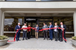 A group of people cut a ribbon in front of a building