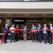 A group of people cut a ribbon in front of a building