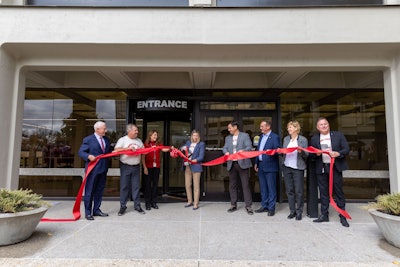 A group of people cut a ribbon in front of a building