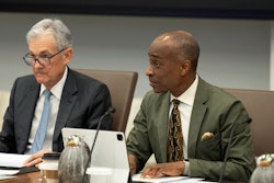 Two men sit at a conference table.