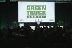 A man speaks on stage in front of a screen that reads Green Truck Summit