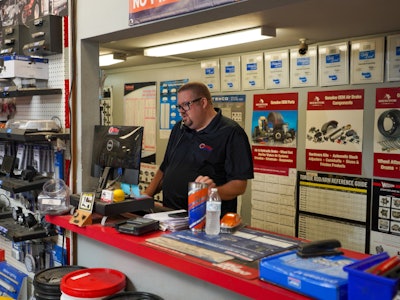 A man talks on the phone behind a counter in a parts store