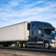 A truck goes down the road in an arid landscape.