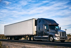 A truck goes down the road in an arid landscape.