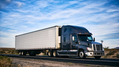 A truck goes down the road in an arid landscape.