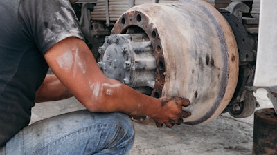 Technician replacing an old brake drum