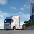 A Hyundai hydrogen fuel cell truck rolls down a ramp in front of a blue sky.