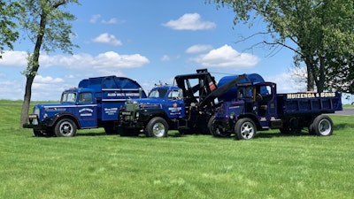 Three antique refuse trucks made by Mack Trucks