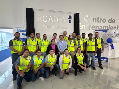 A group of people standing in front of a Value Stream Academy sign at a Bendix plant