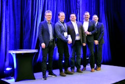 A group of men on a stage with an award.