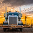 A truck in the desert against a sunset background.