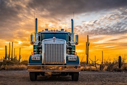 A truck in the desert against a sunset background.