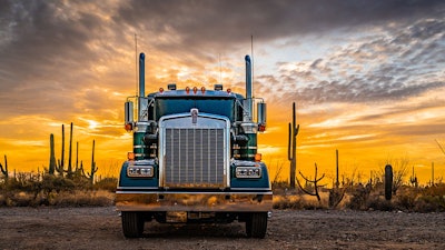 A truck in the desert against a sunset background.