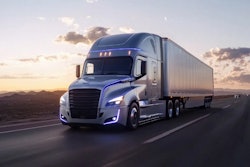 A Freightliner truck traveling on the highway at dusk.