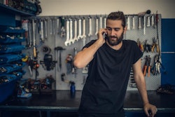 A man on the phone in a mechanic shop