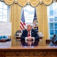 President Donald Trump sits at the Resolute Desk in the Oval Office.