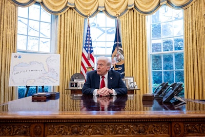 President Donald Trump sits at the Resolute Desk in the Oval Office.