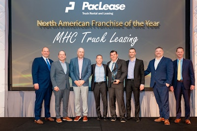 A group of men stand on stage in front of a sign that says, 'PacLease Truck Rental and Leasing North American Franchise of the Year: MHC Truck Leasing.'