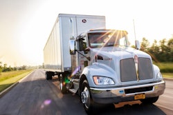 A truck pulling a Great Dane trailer down the road.