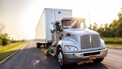 A truck pulling a Great Dane trailer down the road.