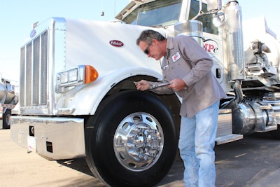 A field service technician measures tread depth on a steer tire to evaluate wear patterns and drivability issues.