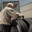A driver measures tread depth on a drive tire to evaluate wear patterns and drivability issues.