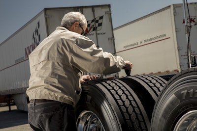 A driver measures tread depth on a drive tire to evaluate wear patterns and drivability issues.