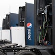Pepsi-branded Tesla Semis parked at a charging stalls.