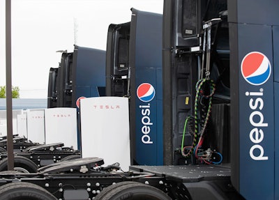 Pepsi-branded Tesla Semis parked at a charging stalls.