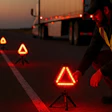 Road safety worker placing glowing warning triangles at sunset