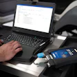 Technician working on laptop with diagnostic device connected