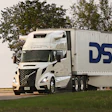 White DSV semi-truck with trailer driving on highway surrounded by green trees