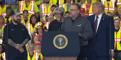 Patrick McHugh stands on stage alongside his father and his son and President Donald Trump. The three generations of McHughs family have spent a combined 78 years building Mack Trucks.