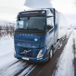 Volvo hydrogen-powered truck driving on snowy winter road through mountainous landscape