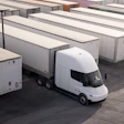 White Tesla Semi electric truck parked among cargo trailers in a logistics yard