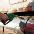 Person holding green fuel pump nozzle at gas station truck with amber lights