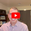 Man in pink shirt smiling in office with YouTube play button overlay