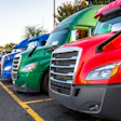 Row of colorful commercial semi-trucks parked at a truck stop facility
