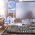 Computer workstation with monitor and keyboard in an automotive service facility with vehicles in background