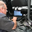 Technician using diagnostic laptop inside vehicle during maintenance inspection