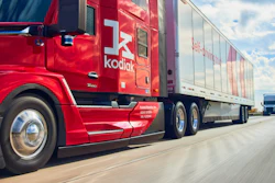 Red Kodiak semi-truck with trailer driving on highway under blue sky