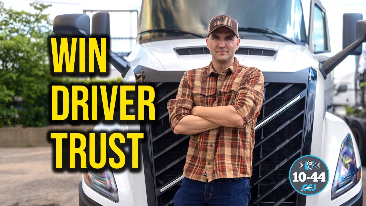 Professional truck driver in plaid shirt standing confidently in front of white commercial truck with 'Win Driver Trust' text overlay