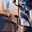 Row of commercial semi-trucks parked in line during sunset with warm golden lighting