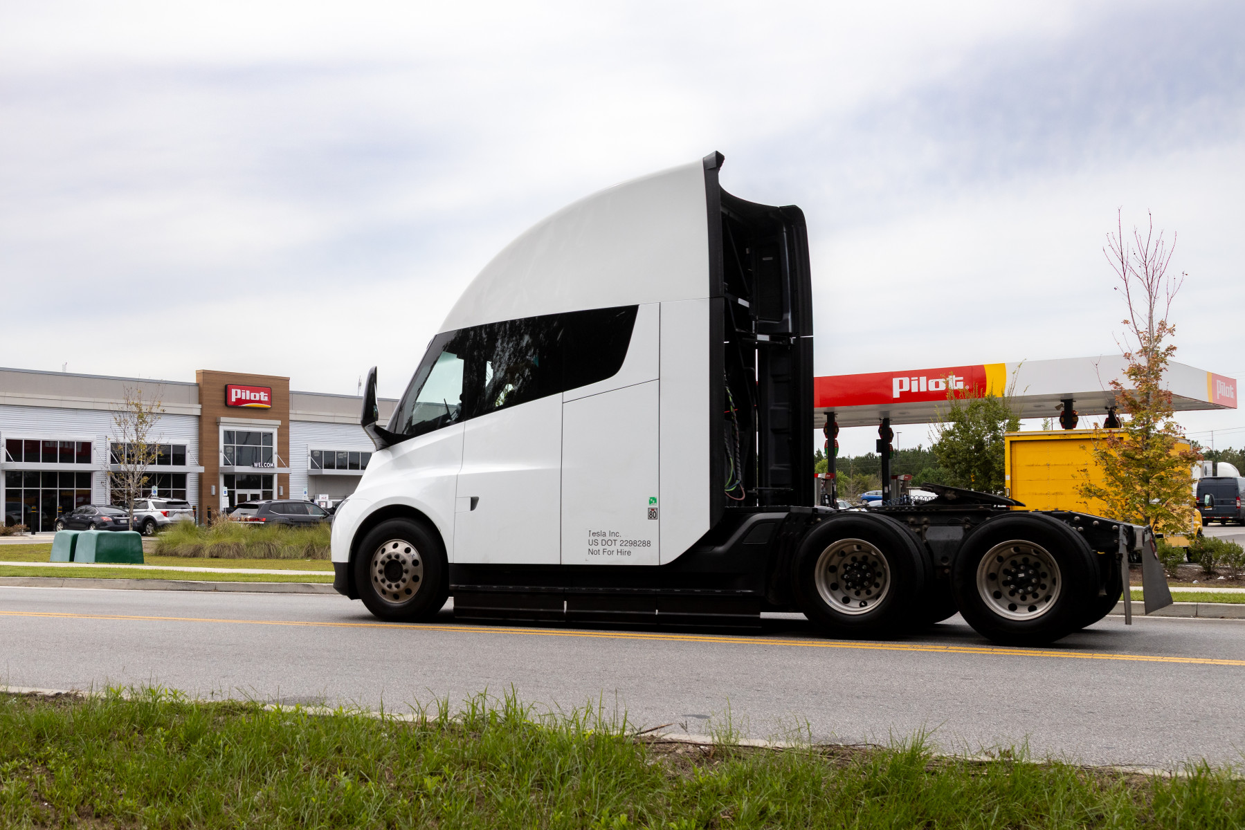 White semi-truck with black accents parked at commercial facility with Penske signage visible