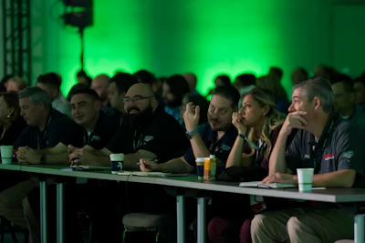 Group of professionals seated at a table during a panel discussion with green ambient lighting in the background.