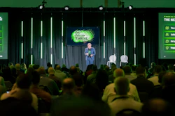 Speaker presenting at 'Go Grow Thrive' conference on stage with audience and green neon lighting