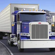 Blue and white Peterbilt semi-truck with cargo trailer driving on mountain highway